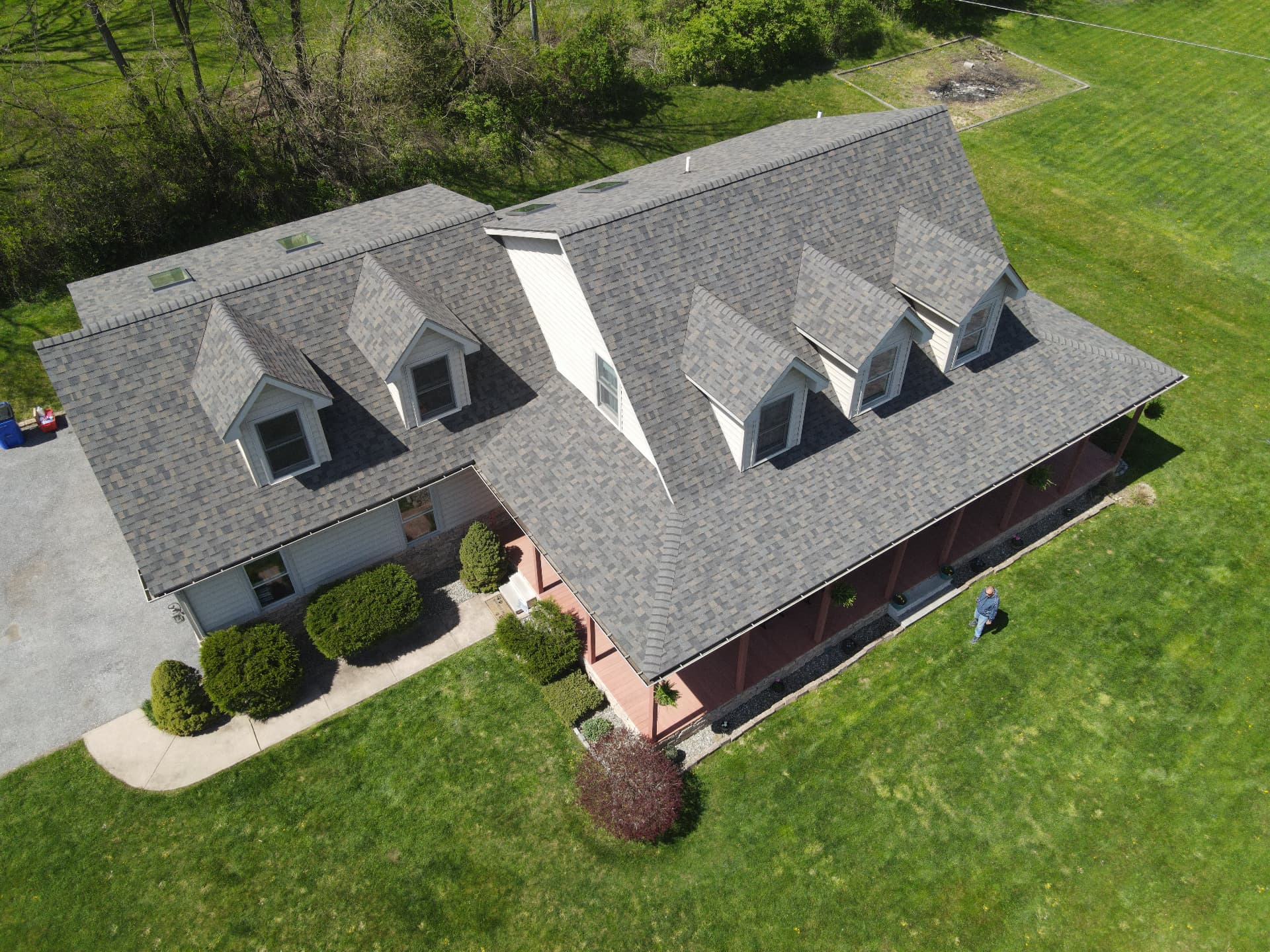 Aerial view of a home with dormers and a finished shingle roof