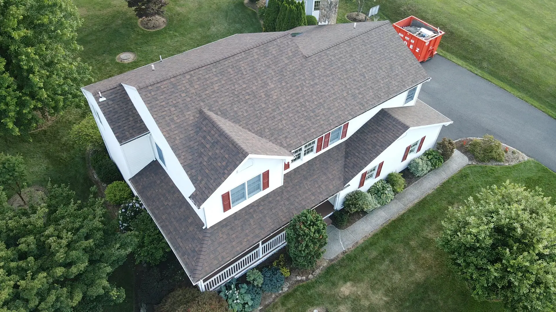Aerial view of a white home with a newly shingled roof