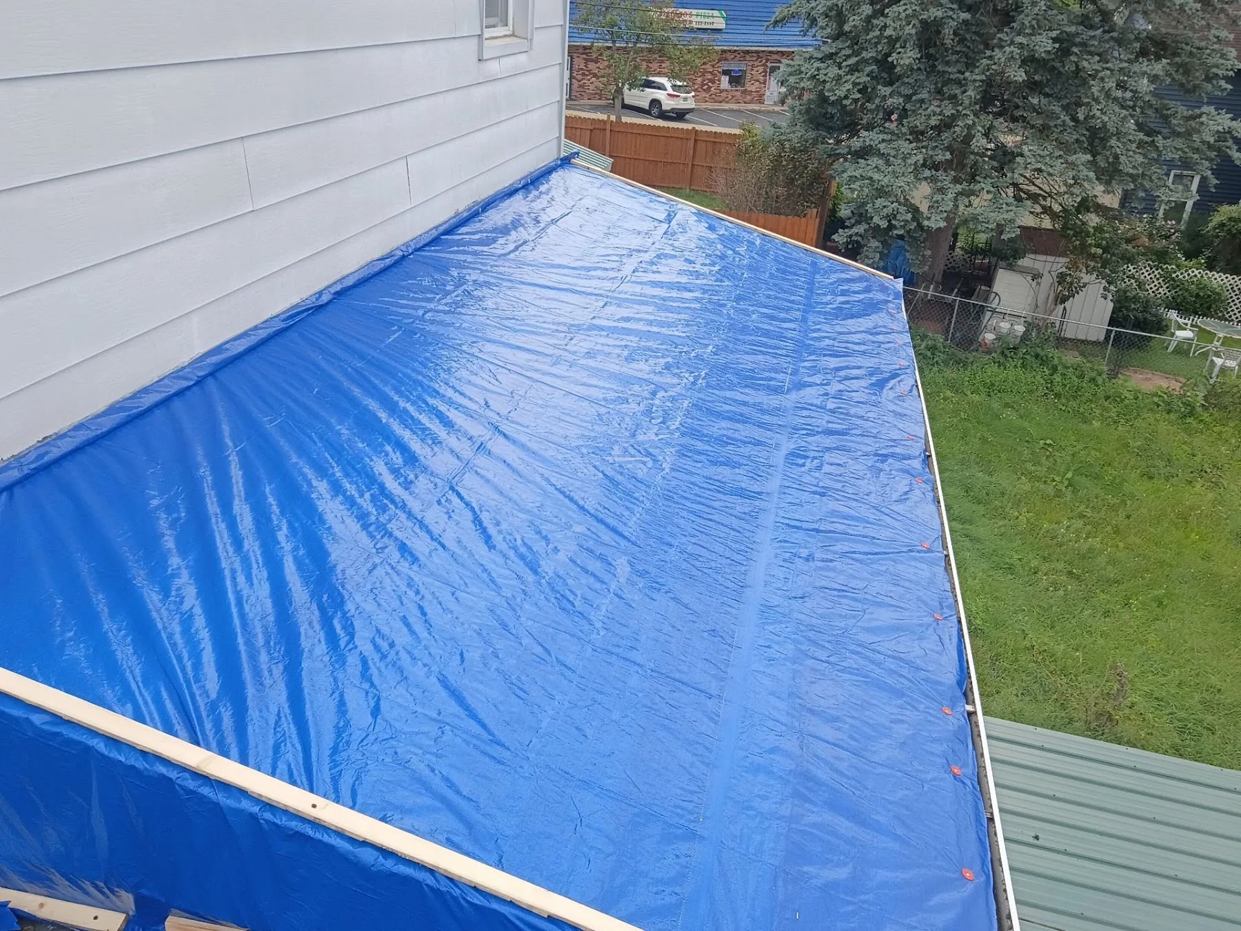 Blue tarp secured over a lower roof