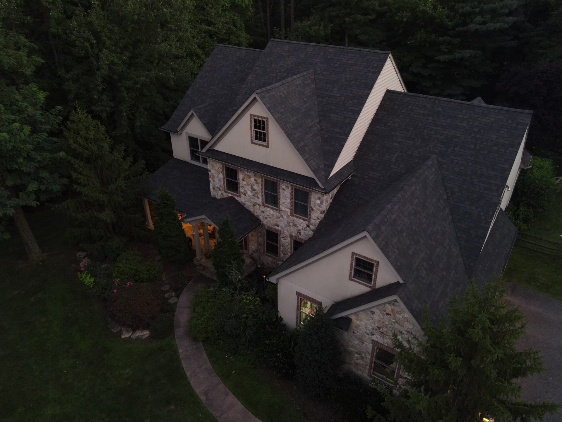 Stone and siding home with a new roof at dusk